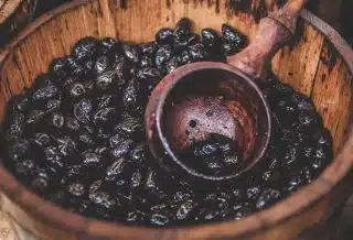 A close-up of a bucket full of cocoa beans and a wooden ladle in Cambridge.
