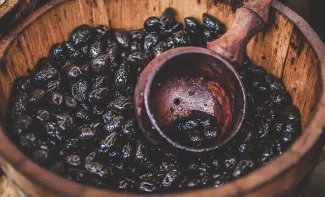 A close-up of a bucket full of cocoa beans and a wooden ladle in Cambridge.